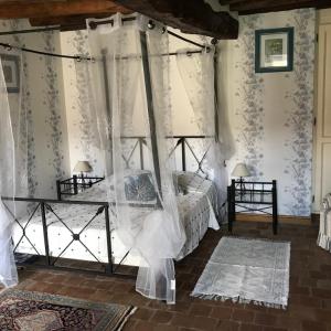 a bedroom with a canopy bed with white curtains at Le Logis de la Pataudière in Champigny-sur-Veude