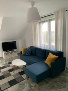 a living room with a blue couch and a tv at Apartamenty Wydminy in Wydminy
