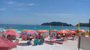 a group of people sitting under umbrellas on a beach at Vila de Sol in Bombinhas