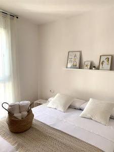 a white bedroom with a bed with a basket on it at Dorada Apartments in Calafell