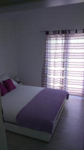 a bedroom with a large bed and a window at Apartman Laura in Tribunj