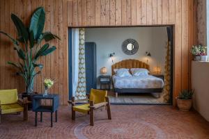 a bedroom with a bed and chairs and a mirror at La Remise Penthouse in Le Somail +31 photos