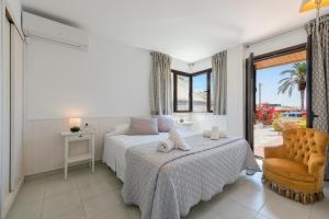 een slaapkamer met een bed, een stoel en een raam bij Apartment La Bugambilia in Port de Pollença