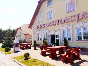 un restaurante con mesas y bancos frente a un edificio en Hotel Magnat, en Ostrowiec Świętokrzyski