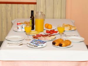 un tavolo con piatti di cibo e bicchieri di succo d'arancia di Hotel Querol a Valderrobres