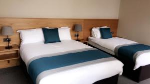 two beds in a hotel room with blue pillows at Belfast House in Cookstown