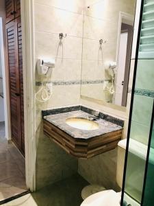 een badkamer met een wastafel en een spiegel bij Flat Amarilis und 110 Riviera de Sao Lourenco SP in Riviera de São Lourenço