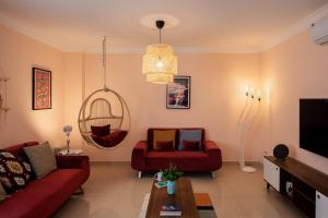 a living room with a red couch and a tv at Two Swings & A Pool - 5 min to Airport in Cairo