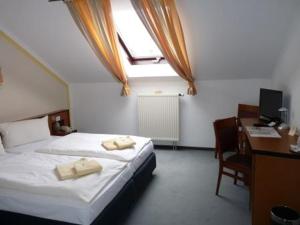 Schlafzimmer mit einem Bett und einem Schreibtisch mit einem Computer in der Unterkunft Hotel zur Kanone in Tautenhain