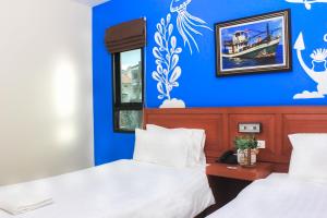 two beds in a room with a blue wall at Krabi P.N. Boutique House in Krabi town