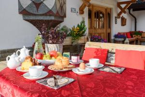 a table with a red table cloth with food on it at Garnì Bel Air in Colfosco