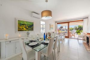 a dining room with a glass table and white chairs at Apartment La Bugambilia in Port de Pollensa +13 photos