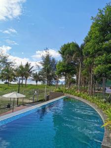 Kampung Sungai KarangにあるTIMURBAY by Fifth'D STUDIOの青いスイミングプール(傘、木付)