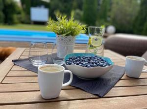 a table with a bowl of blueberries and cups of coffee at Pokoje Gościnne Zielony Dom in Frombork