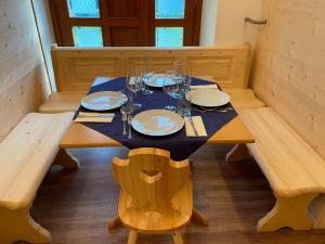 una mesa de madera con platos y copas de vino. en Casa Ortis, en Paluzza