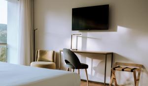 a hotel room with a bed and a chair and a television at Monte Prado Hotel & Spa in Melgaço