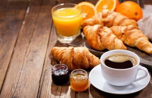 a table with a cup of coffee and croissants and orange juice at Hotel Choiseul Opera in Paris