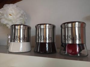 trois tasses en métal assises sur une étagère avec une fleur dans l'établissement 2BCENTRAL, à Desenzano del Garda