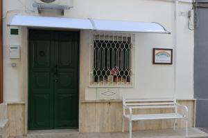 una porta verde e una panchina di fronte a un edificio di Casa Vacanza Arcobaleno a Oria