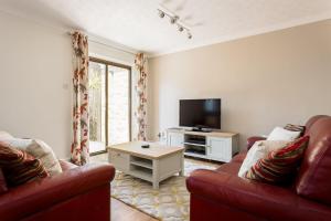 een woonkamer met twee rode banken en een tv bij Sanderling in Poole