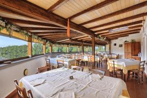 un comedor con mesas, sillas y ventanas en Oleandri Suite Hotel, en Vada