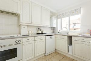een witte keuken met witte kasten en een wastafel bij Sanderling in Poole