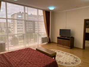 a bedroom with a bed and a tv and a large window at Hotel Continent in Groznyy