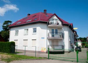a large white house with a red roof at Apartament IKAR blisko morza in Pobierowo