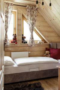 a bed in a room with wooden walls and windows at Bukowy Raj in Wisła