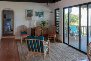 una sala de estar con sillas y un porche con puertas correderas de cristal. en VILLA DEL SOLE en Virgin Gorda