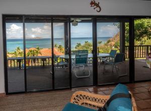 a living room with a balcony with a table and chairs at VILLA DEL SOLE in Virgin Gorda