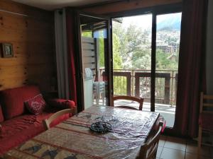 a living room with a table and a couch and a balcony at Le Signal Du Prorel in Briançon