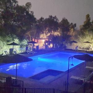 - une grande piscine bleue la nuit avec des parasols dans l'établissement Camping & Hôtel Le Calme, à Essaouira