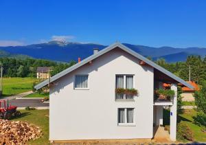 a white house with flowers on the windows at Apartman Lukić in Korenica