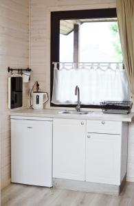 a kitchen with white cabinets and a sink and a window at A Morze Ustka in Ustka
