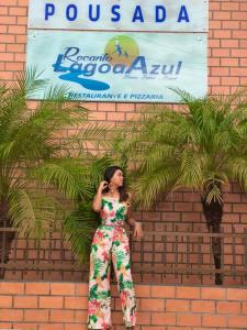 a woman standing in front of a brick wall talking on a cell phone at Pousada Recanto Lagoa Azul in Baixio