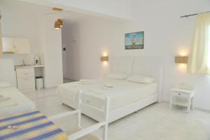 een witte kamer met een bed en een keuken bij Hotel Apartments Giannis in Adamas