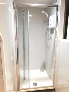 een douche met een glazen deur in de badkamer bij Uwch Menai in Y Felinheli