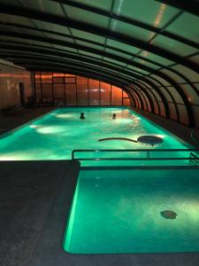 duży basen z zielonym oświetleniem w budynku w obiekcie Dom nad morzem 250m od plaży Międzywodzie w mieście Międzywodzie