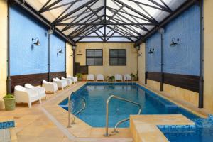 ein Schwimmbecken in einem Gebäude mit Stühlen drumherum in der Unterkunft Hotel Leoncia in Colonia del Sacramento