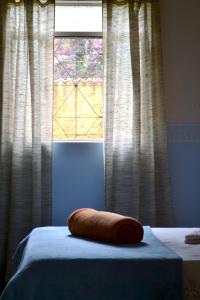 a pillow on a bed in front of a window at Hostel Tiradentes in Tiradentes