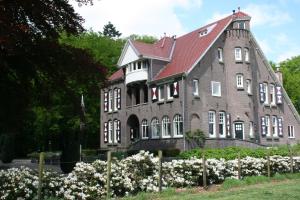 ein großes Backsteingebäude mit rotem Dach in der Unterkunft Villa Rozenhof in Almen