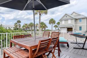 einem Holztisch mit Stühlen und einem Sonnenschirm auf einer Terrasse in der Unterkunft Atlantic Shores Getaway steps from Jax Beach Private House Pet Friendly Near to the Mayo Clinic - UNF - TPC Sawgrass - Convention Center - Shopping Malls - Under 3 Hours from DISNEY in Jacksonville Beach