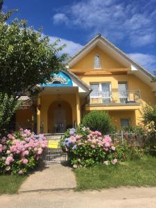 a yellow house with pink flowers in front of it at SŁONECZNIK in Rewal