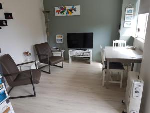 a living room with a dining table and a television at Achter de Beukenboom in Roden