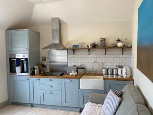 een keuken met blauwe kasten en een wastafel bij Little Dolly sea view 2 bedroom apartment, St Ives town, dog friendly in St Ives
