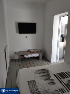 Dieses weiße Zimmer verfügt über einen TV an der Wand. in der Unterkunft Logement avec Spa Privatif Jacuzzi Grande terrasse sans vis à vis Sky House Agen in Agen