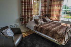 a bedroom with a bed and a chair and a window at The Knock Guest house in Dunhill