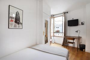 a white bedroom with a bed and a desk at Zazie Hôtel in Paris