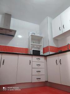 kuchnia z białymi szafkami i czerwoną ścianą w obiekcie Apartamento Santa Ana Ronda w mieście Ronda +16 zdjęć